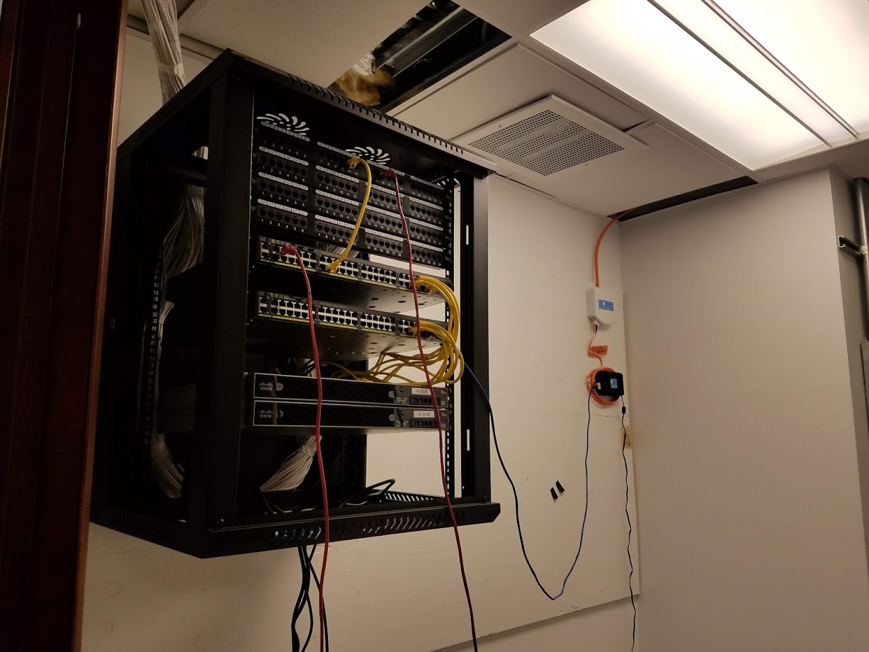 Wall-mounted commercial network rack with patch panels and switches